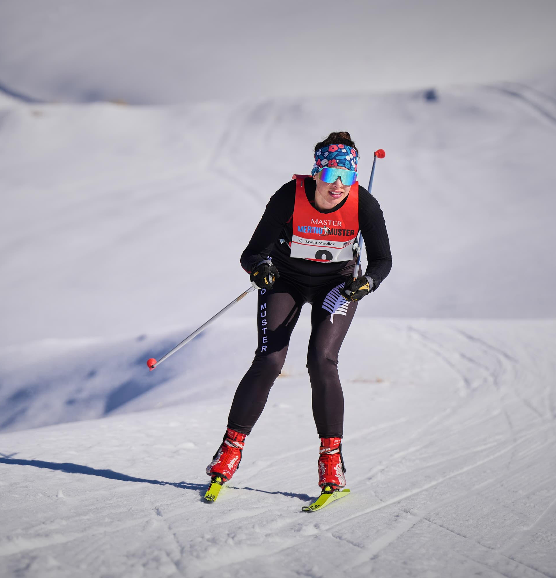 Snow Farm Wanaka Cross-country skier in red race bib climbing snowy slope with ski poles, winter alpine race competition